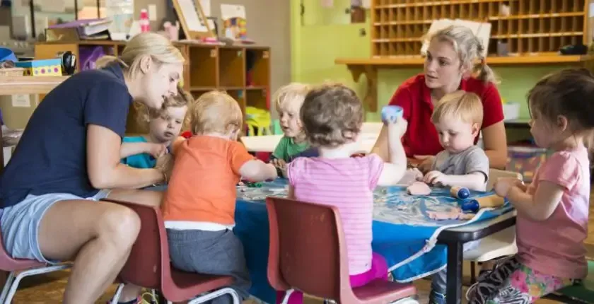 Decorative image of two childcare workers and a group of kids